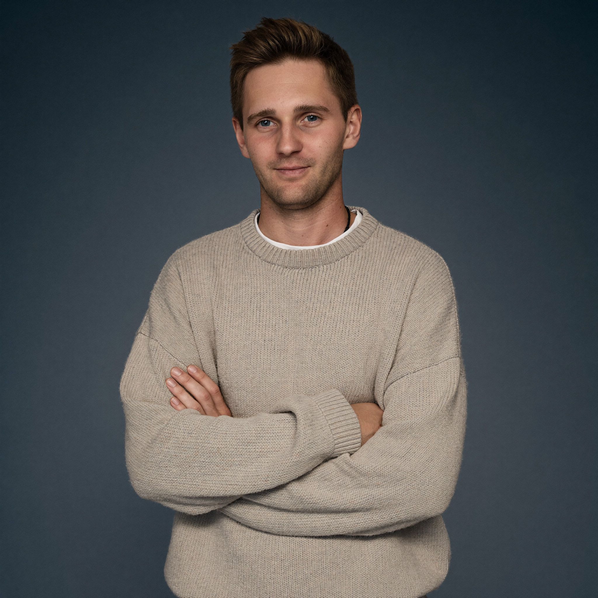 Kevin Baum im hellen Strickpullover mit verschränkten Armen.